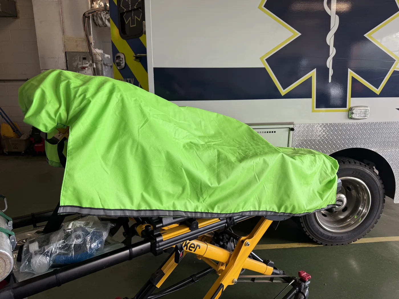 Angled view of covered stretcher with ambulance